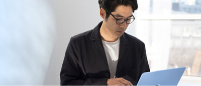 A man wearing glasses and a white shirt using a laptop.