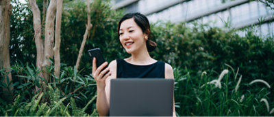 A woman holding a phone and a laptop.