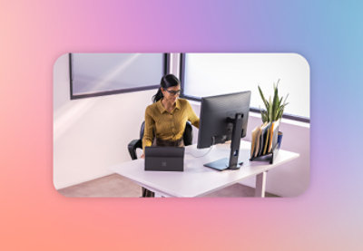 A woman in a yellow shirt sitting at a desk working on a computer.
