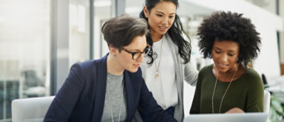 Um grupo de mulheres olhando para um laptop.