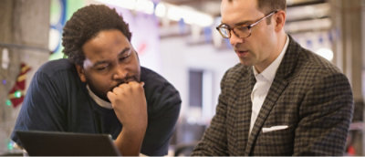 Ein Mann mit Brille, der auf einen Laptopbildschirm blickt.