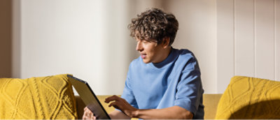 A man sitting in a sofa looking at a laptop.