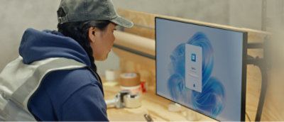 Une femme portant une veste bleue regardant un écran d'ordinateur.