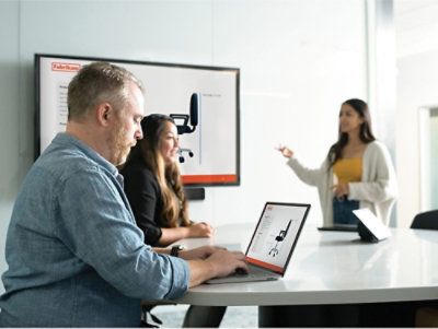 A man and woman sitting at a desk with a laptop.