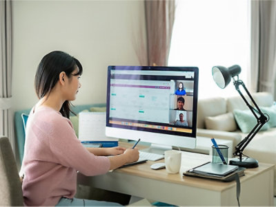 A woman sitting at a desk looking at a computer screen.