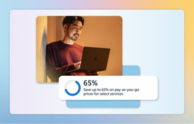 A man in a red shirt holding a laptop in front of a sign with a promotional offer for select services.