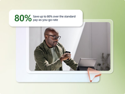 En mann med briller, iført en grønn jakke, smiler mens han bruker en bærbar datamaskin og smarttelefon. Et tekstoverlegg sier «80 % spar opptil 80 % sammenlignet med standard forbruksbetalingssats».