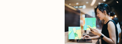 A women holding mobile and looking into laptop.