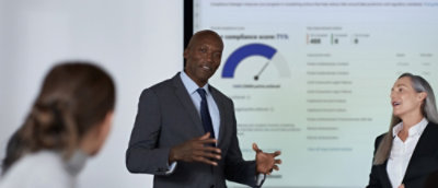 Un bărbat și o femeie stând în fața unui ecran mare.