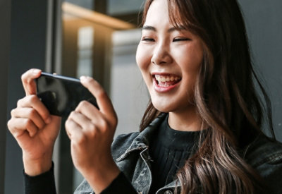 Person with long hair holding a smartphone horizontally.