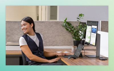 Person sitting at a desk in an office, looking at two computer monitors