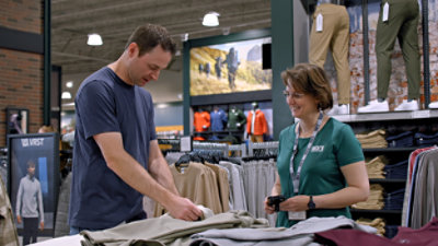 A man and woman in a clothing store looking at clothes.