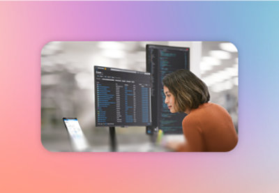 A woman in an orange shirt looking at a computer screen