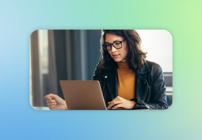 A woman with long hair wearing glasses is looking at a laptop.