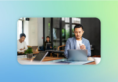 A person holding a cup of coffee and using a laptop