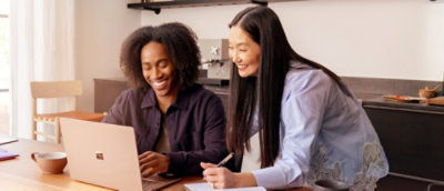 Two people smiling while looking at the screen.