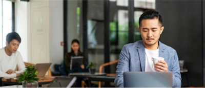 Image 72: A man in a suit holding a cup and looking at a laptop.
