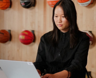 一位穿着黑色衬衫的女士坐在笔记本电脑前面。