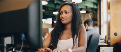 白いシャツを着てコンピューターの前に座っている女性。