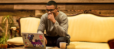 顔に手を当ててノート PC を見ている男性。