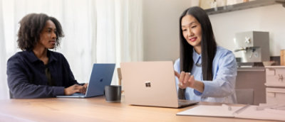 A couple of people sitting at a table with laptops.