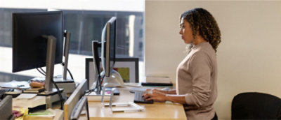 机に向かって座り、コンピューターを使用している女性。