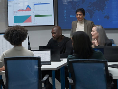 A group of people sitting around a table with laptops.