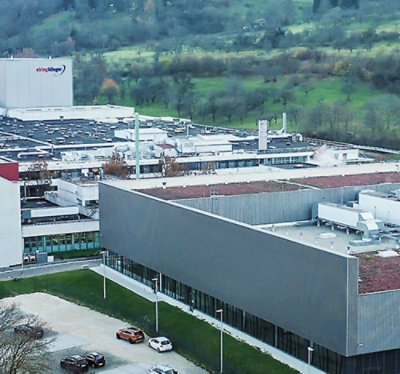 A quaint suburban house with a well-manicured garden, featuring two chairs on the lawn and vibrant flowering 
