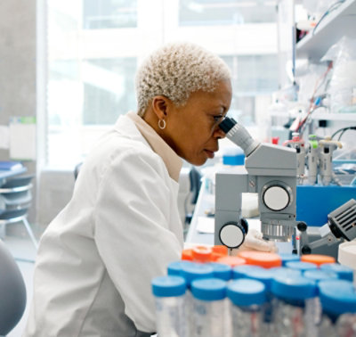 Donna che guarda in un microscopio in un laboratorio.