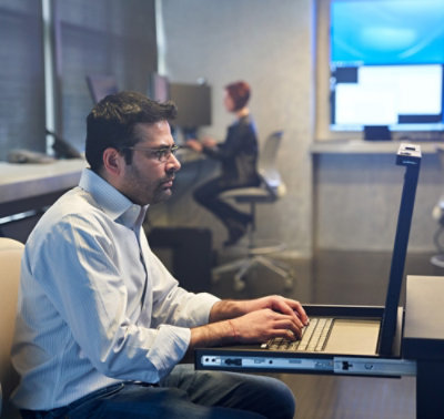 Uomo seduto alla scrivania che lavora a un portatile.