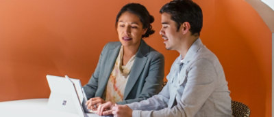 Uomo e donna seduti a un tavolo che guardano un portatile.