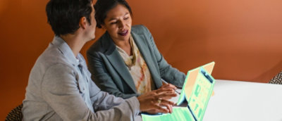 A man and woman sitting at a table with a laptop.