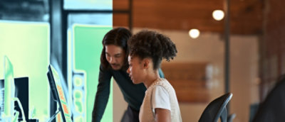 Two people collaborating at a desk with a computer in a modern office.