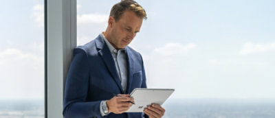 A man in a suit is holding a tablet in his hands.