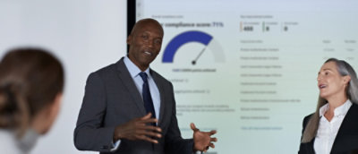 A man and woman standing in front of a large screen.