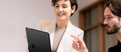 A woman and a man are looking at a tablet in an office.
