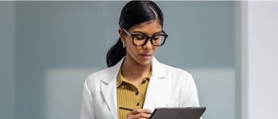 A woman in a white coat holding a pen.