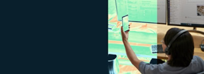 A woman holding a phone wearing headphones.