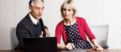A man and woman looking at a laptop.