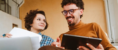 A man holding a tab and explaining something to a women.