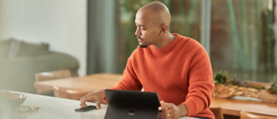 A person in an orange sweater using a laptop.