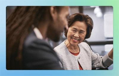 Two individuals are engaged in a conversation. The woman is smiling while looking at the man.