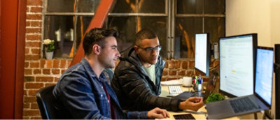 Two people are looking at a computer screen.