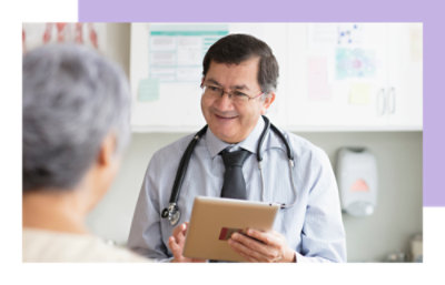 A doctor holding a tablet while speaking to a patient.
