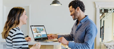 Un hombre con una camiseta azul mira un portátil.