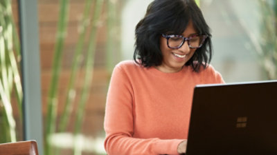 A person wearing an orange shirt and using a laptop.