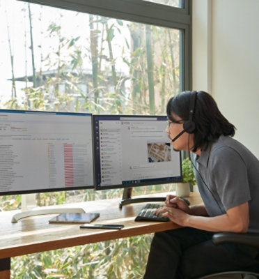  A person wearing headphones and using a computer at a desk.