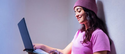 Osoba siedząca i trzymająca laptopa.