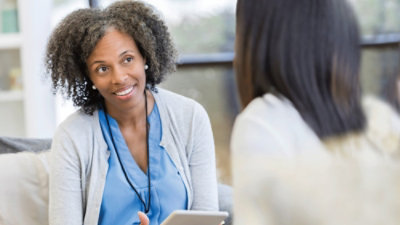 A woman is engaged in conversation with another woman, both appearing attentive and interested in the discussion.