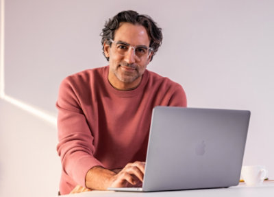 A men wearing spects and working with a laptop.